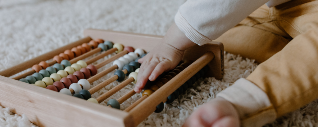 Houten speelgoed telraam waar een baby mee speelt